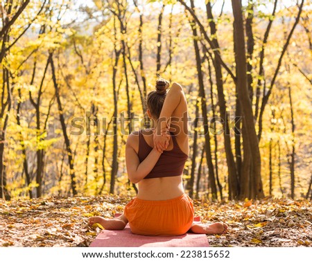 Young woman doing yoga in morning park. Young girl of Caucasian ethnicity outside doing yoga asana in autumn