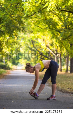 Fitness woman doing stretching during outdoor cross training workout. Beautiful young and fitness sport model training outside