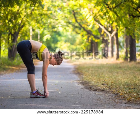 Fitness woman doing stretching during outdoor cross training workout. Beautiful young and fitness sport model training outside