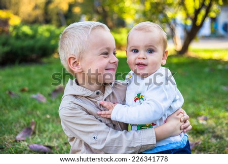 Two cute brothers playing outside in a grassy suburban park