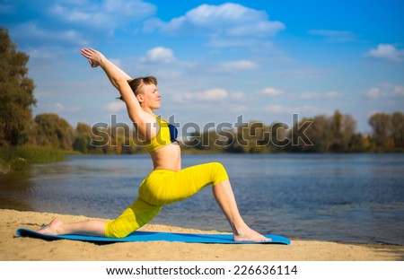 Young woman in yellow clothing doing yoga on the river bank