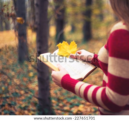 Fall fairy concept -  woman with book and yellow leaf in fall foliage