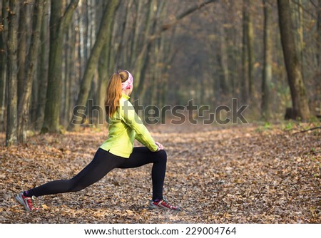 Fitness woman doing stretching during outdoor cross training workout. Beautiful young and fitness sport model training in autumn park outside