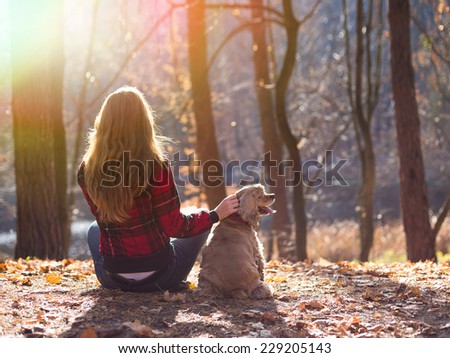 Young woman and her dog (American Cocker Spaniel) sitting outside at fall time