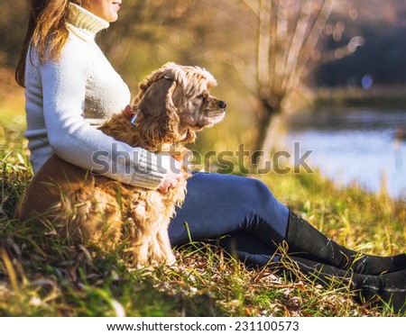 Young woman and her dog (American Cocker Spaniel) posing in park near lake