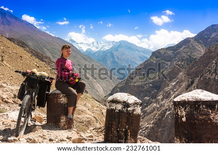 Young woman bicyclist sitting on road in himalayas mountain landscape. Jammu and Kashmir State, North India