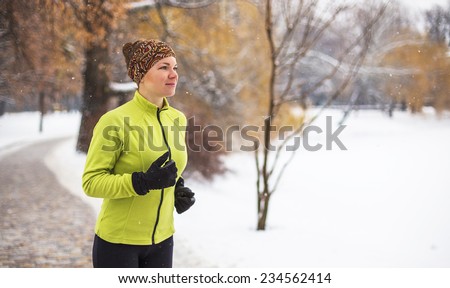Happy smiling young woman running in snowing winter