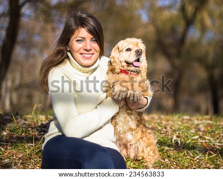 Young pretty woman with her dog American Cocker Spaniel sitting in city park in sun lights in autumn