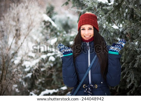 Beautiful young girl posing in winter park near frost evergreen spruce