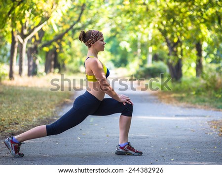 Fitness woman doing stretching during outdoor workout. Beautiful young and fitness sport model training outside