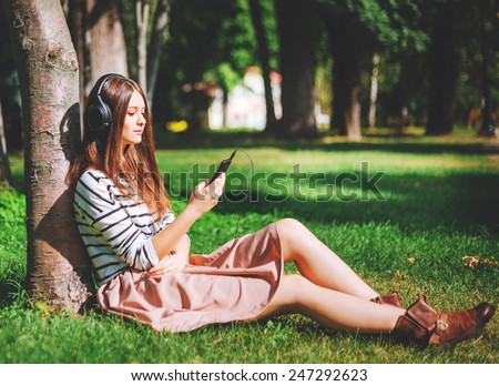 Young girl listening to music in city park
