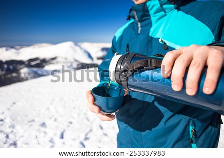 Happy man holding thermos on mountain top in winter