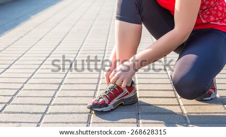 Sport woman tying running shoes during training in park in the morning