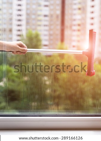 Worker is cleaning window glass with steam in sunny day