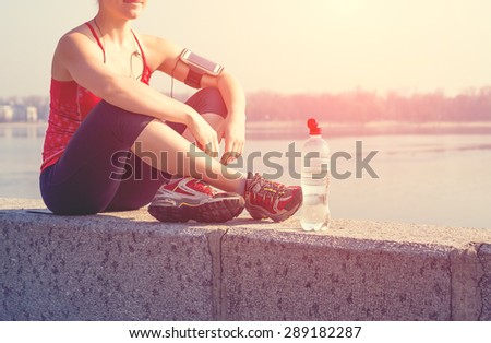 Sport woman having a rest during training outside in city quay in the morning
