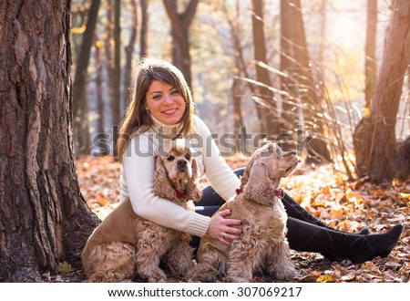 Pretty woman with two beautiful cocker spaniels in autumn park