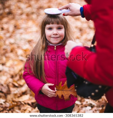 Cute girl with her mother in city park at fall