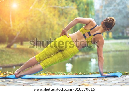Young woman doing yoga in autumn yellow park