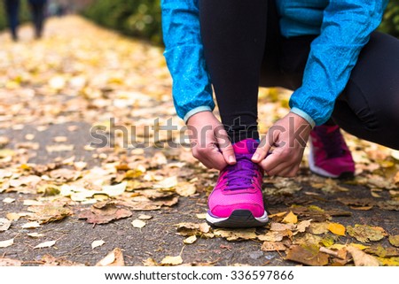 Sport woman tying running shoes during outdoor cross training workout. Beautiful young and fitness sport model training outside.