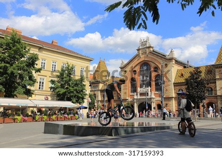 BUDAPEST, HUNGARY, JULY 11,2015: Urban scene with cyclists in front of the  Great Market Hall of Budapest, the largest and oldest indoor market in Budapest, Hungary.