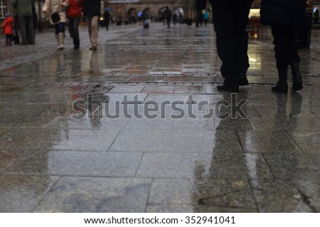 Walking along wet  pavement street. Rain in the city.