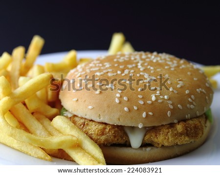 delicious chicken burger soft brown bread with crispy chips closeup on white plate