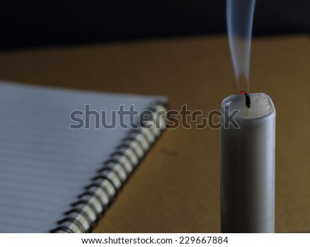 transparent smoke from snuffed candle and a notebook on the table