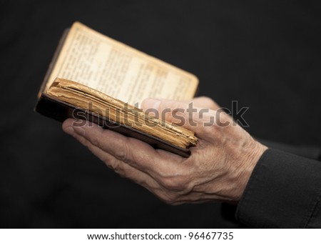 Hands of an old man holding a book