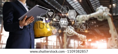 A futuristic architect, Businessman, Engineer manager using tablet with icon network, Industrial robotics, Automation robot arms machine in intelligent construction site. Industry technology concept