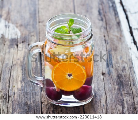 Mug delicious refreshing drink of mix fruits with mint on wooden, infusioned water