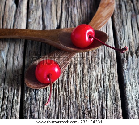 maraschino cherry vibrant on wooden spoon and old table background