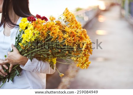 abstract woman with bouquet flowers vibrant colorful in hands on street sunset background, warm tone, soft focus and blur