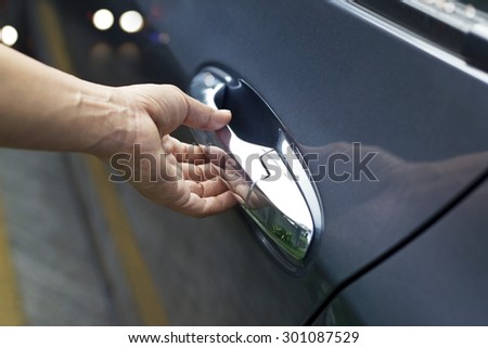 Hand on handle, man opening a car door on the street