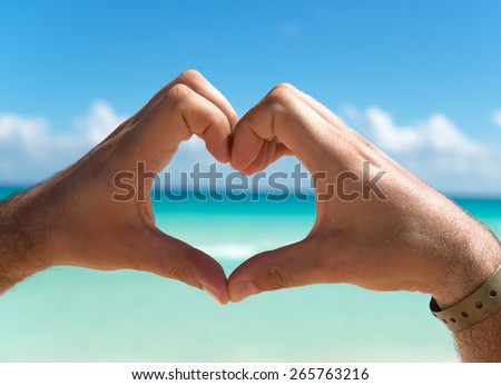 Hands in the shape of heart on the background of the Caribbean Sea