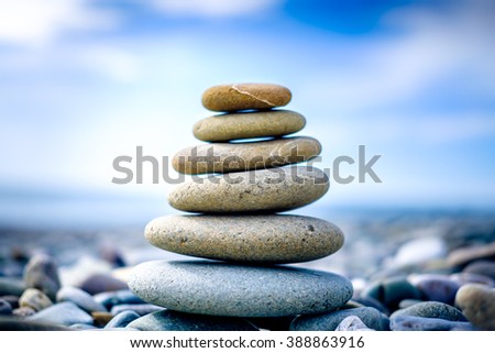 Stones pyramid on pebble beach symbolizing stability, zen, harmony, balance. Shallow depth of field.