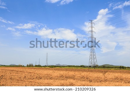 Electricity transmission pylons with blue sky and white cloud in a rural area