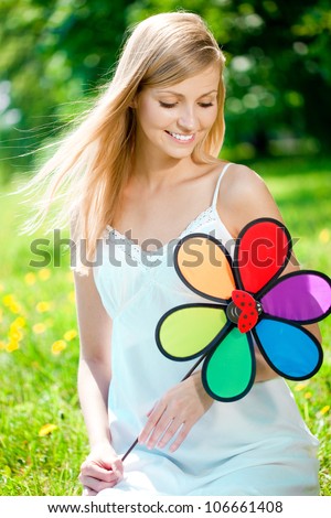 Beautiful smiling woman with a rainbow flower outdoors