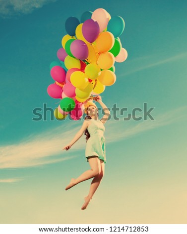 Luxury fashion woman with balloons in hand on the field against the sky and the sun in \
long dress
