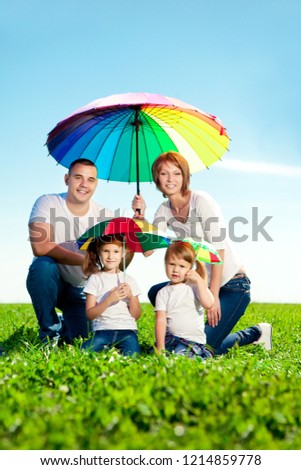 Happy family in outdoor park  at sunny day. Mom, dad and two daughters in the green \
garden.  Group of people on green grass.