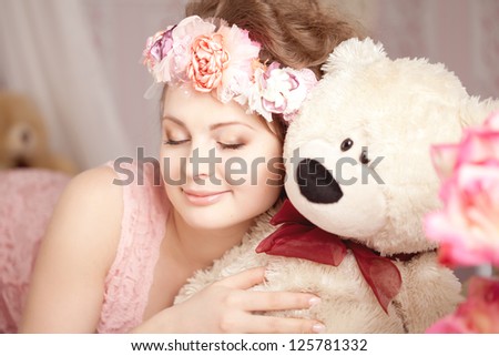 Beautiful woman in a pink room with a toy bear