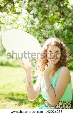 Young woman holding white bubble talk in summer park