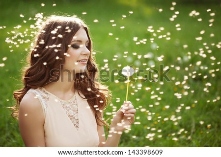 Beautiful young woman blowing a dandelion