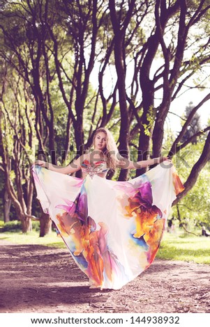 Beautiful woman in a bright dress flying in the forest