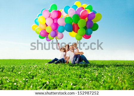 Happy Family Holding Colorful Balloons Outdoor. Mom, Dad And Two Daughters Playing On A Green Meadow.
