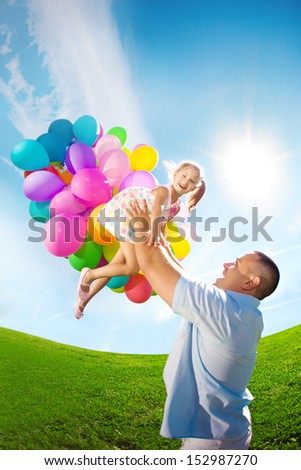 Father throws daughter. Family playing together in park with balloons. Father tosses a baby against the sky