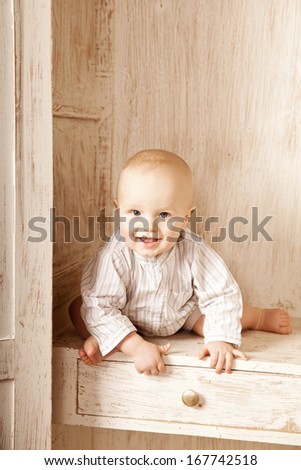Beauty little baby sitting in the closet. Smiling child and interior of a bedroom. Cute kid
