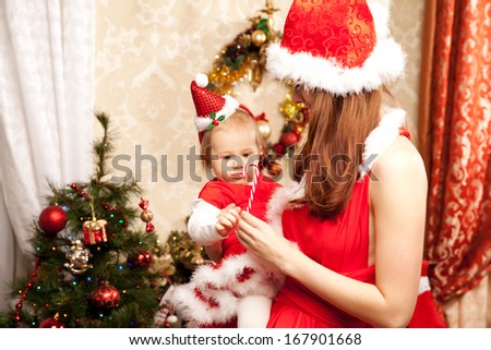 Young family sitting around the Christmas tree. Mom and baby in the New Year  interior.