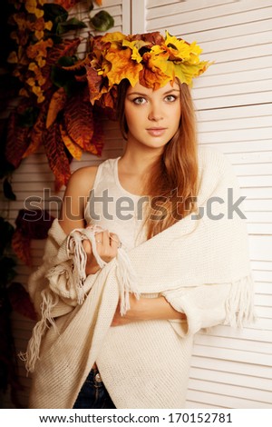 Beautiful autumn woman smiling on the porch of yellow and orange autumn leaves. Stylish autumn girl