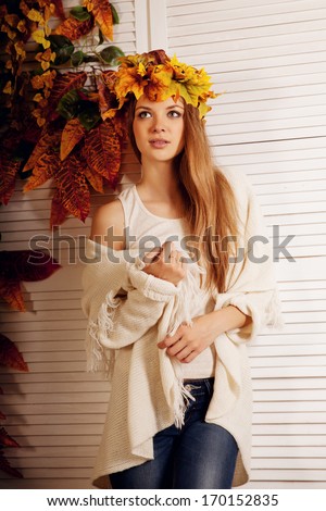 Beauty autumn woman smiling on the porch of yellow and orange autumn leaves. Stylish autumn girl