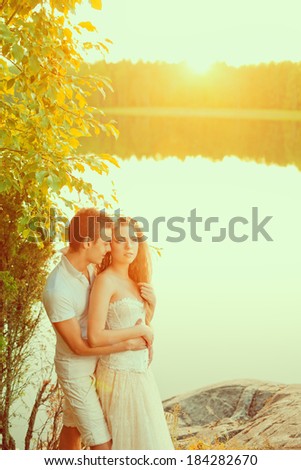Loving couple hugging on the lake. Beautiful young woman and man in the background of the sun shining. Happy smiling Loves a date